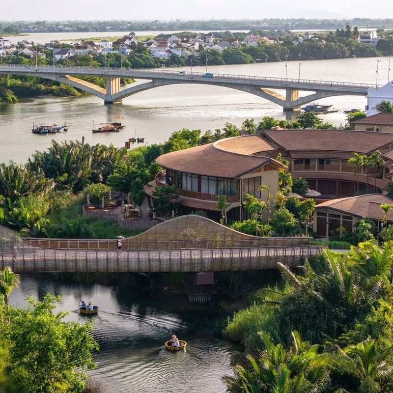 : A bamboo bridge and traditional basket boats on the water near the Namia River Retreat buildings.