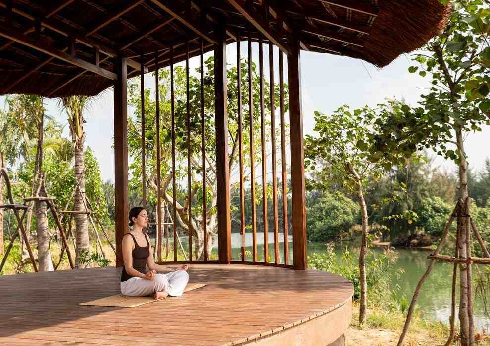 A woman practicing yoga in a wooden riverside pavilion at Namia River Retreat.