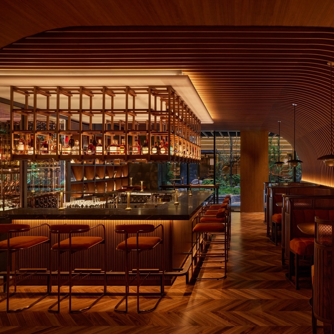Elegant bar with wooden floors, amber lighting, and shelves of liquor bottles.