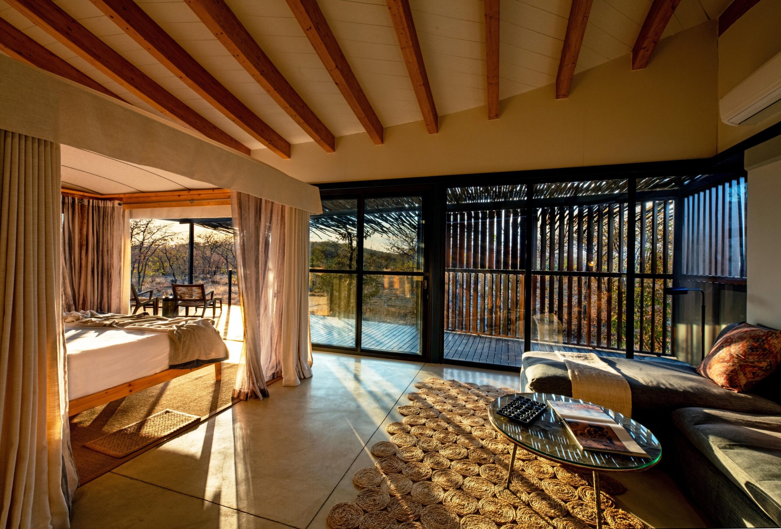 Cozy interior of a room with large windows overlooking a sundrenched landscape.