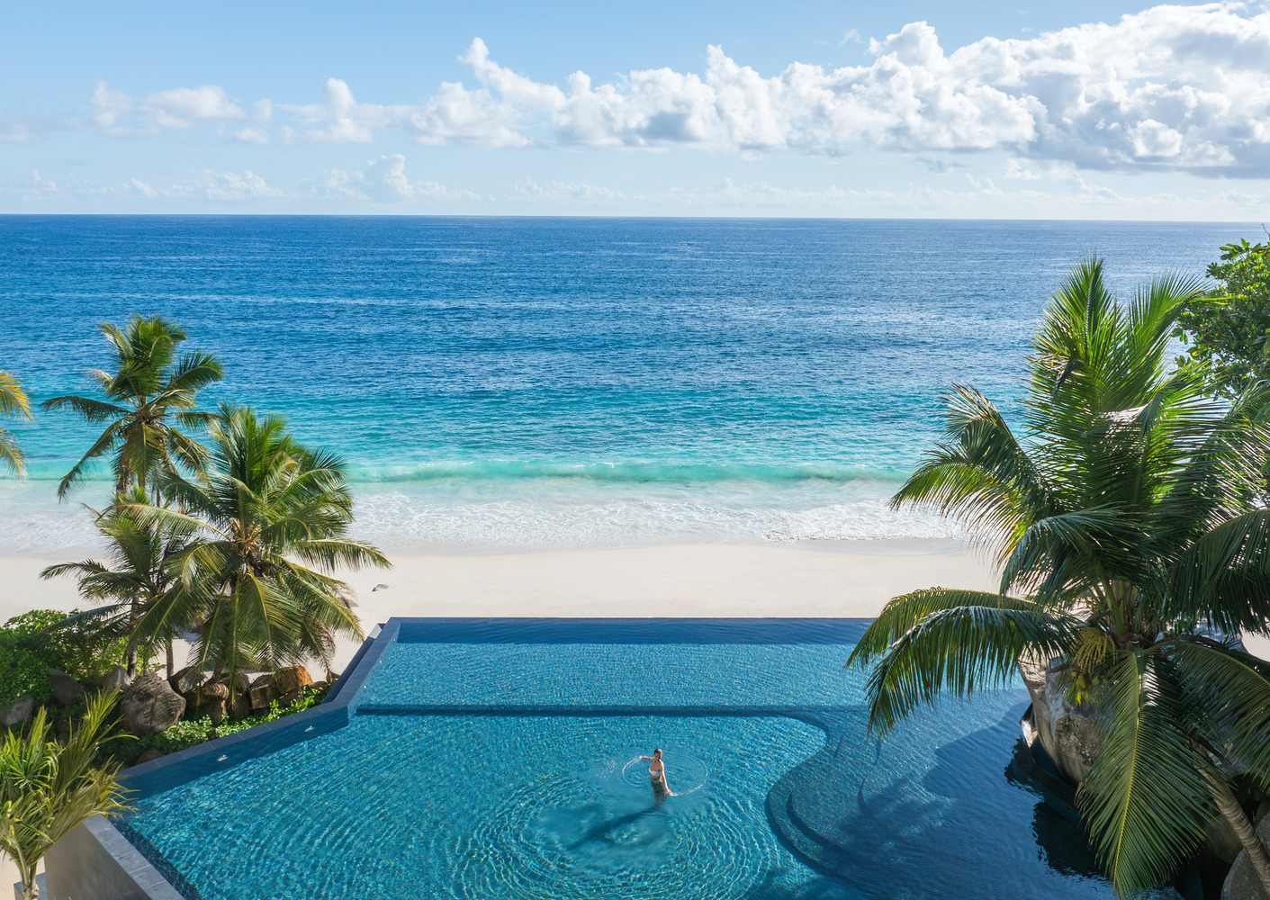 A swimming pool at Cheval Blanc Seychelles overlooking Anse Intendance beach and the Indian Ocean.