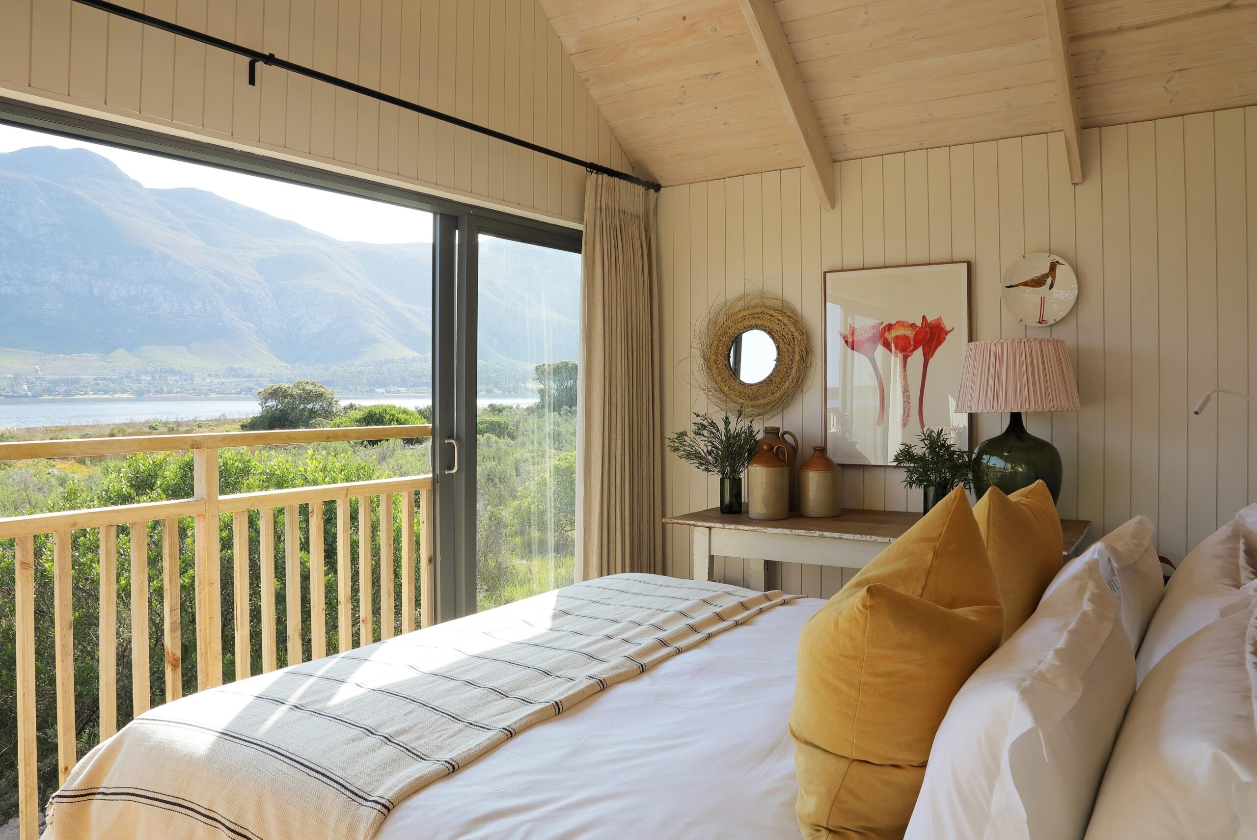 A bedroom in a private boathouse at Coot Club with Maanschynkop mountains in the background.