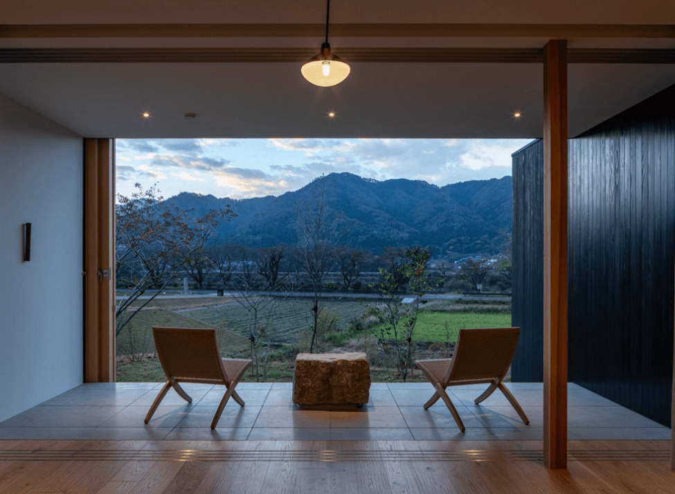 Two chairs on a covered terrace facing a view of mountains at sunset