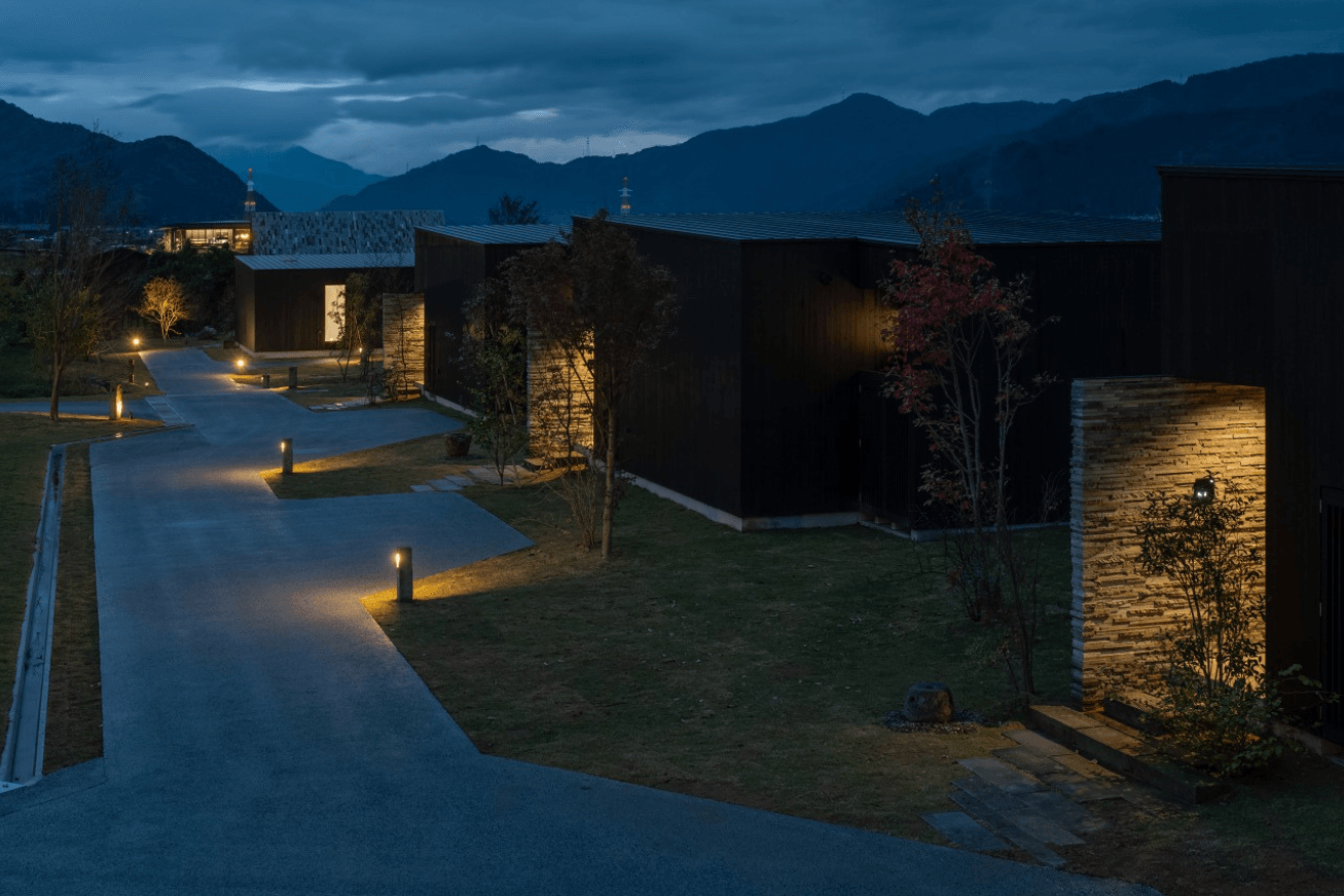 Nighttime exterior view of modern square buildings set along a path