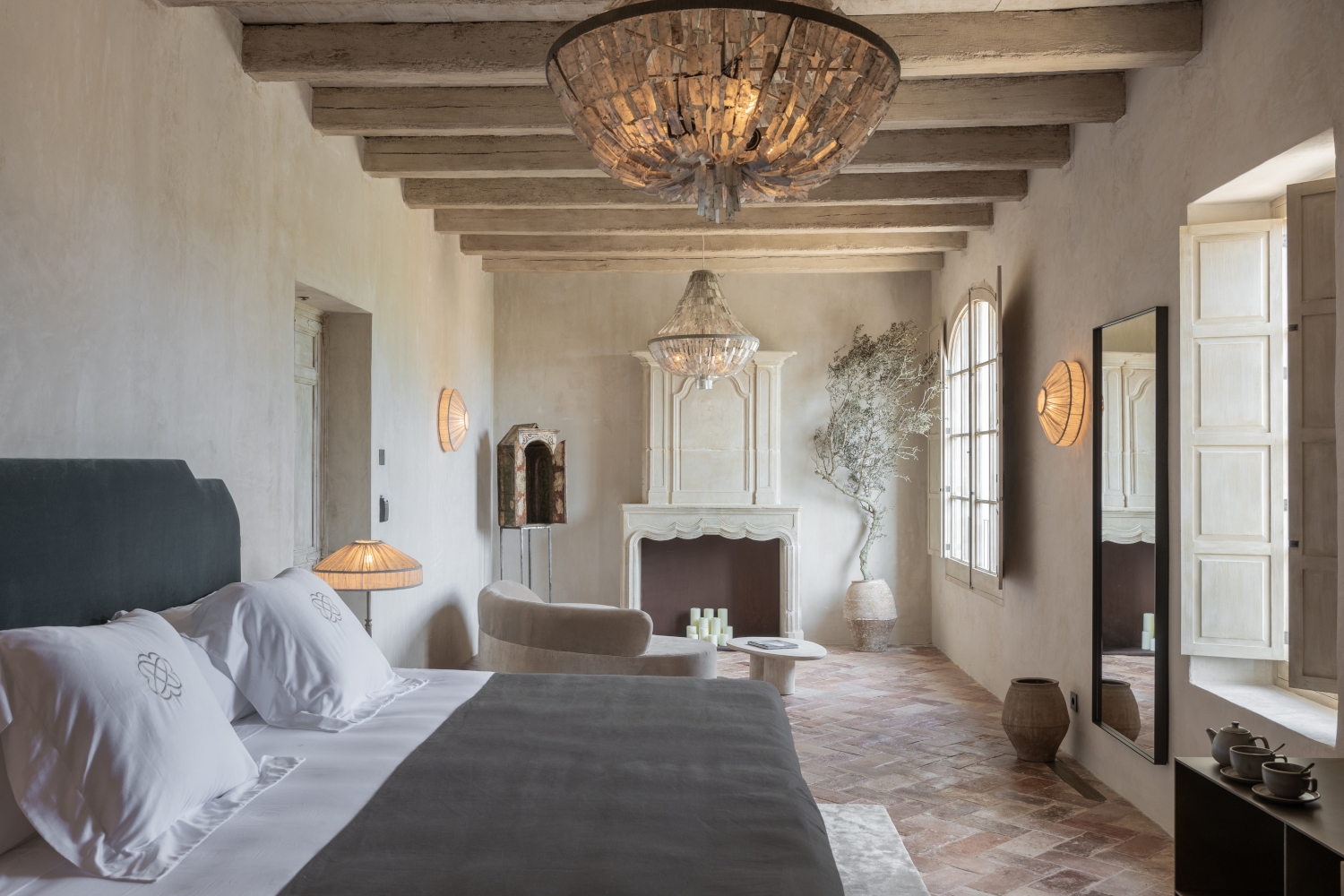 Rustic luxury bedroom at Son Vell in Balearic Islands Spain with wood beams, stone fireplace, and terracotta tile floors.