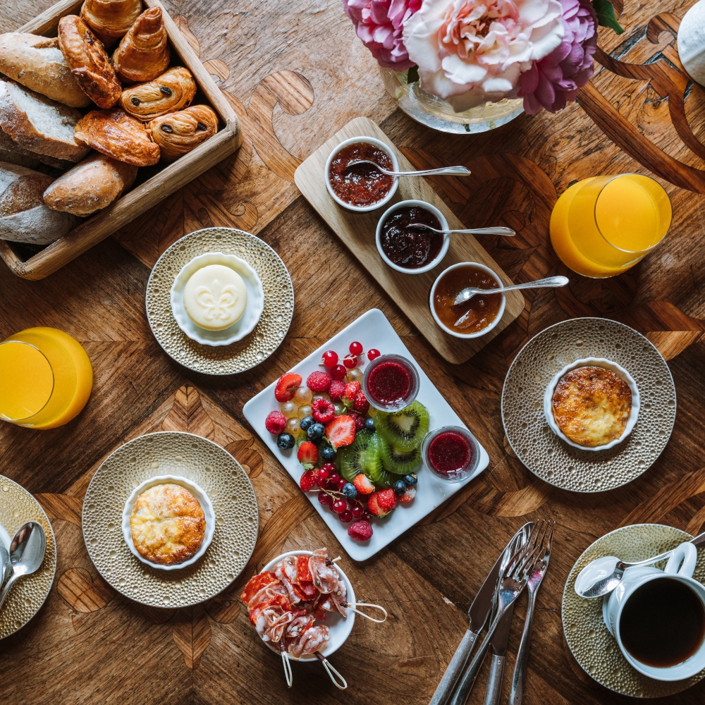 Overhead shot of a wood table covered in breakfast dishes, coffee and juice.