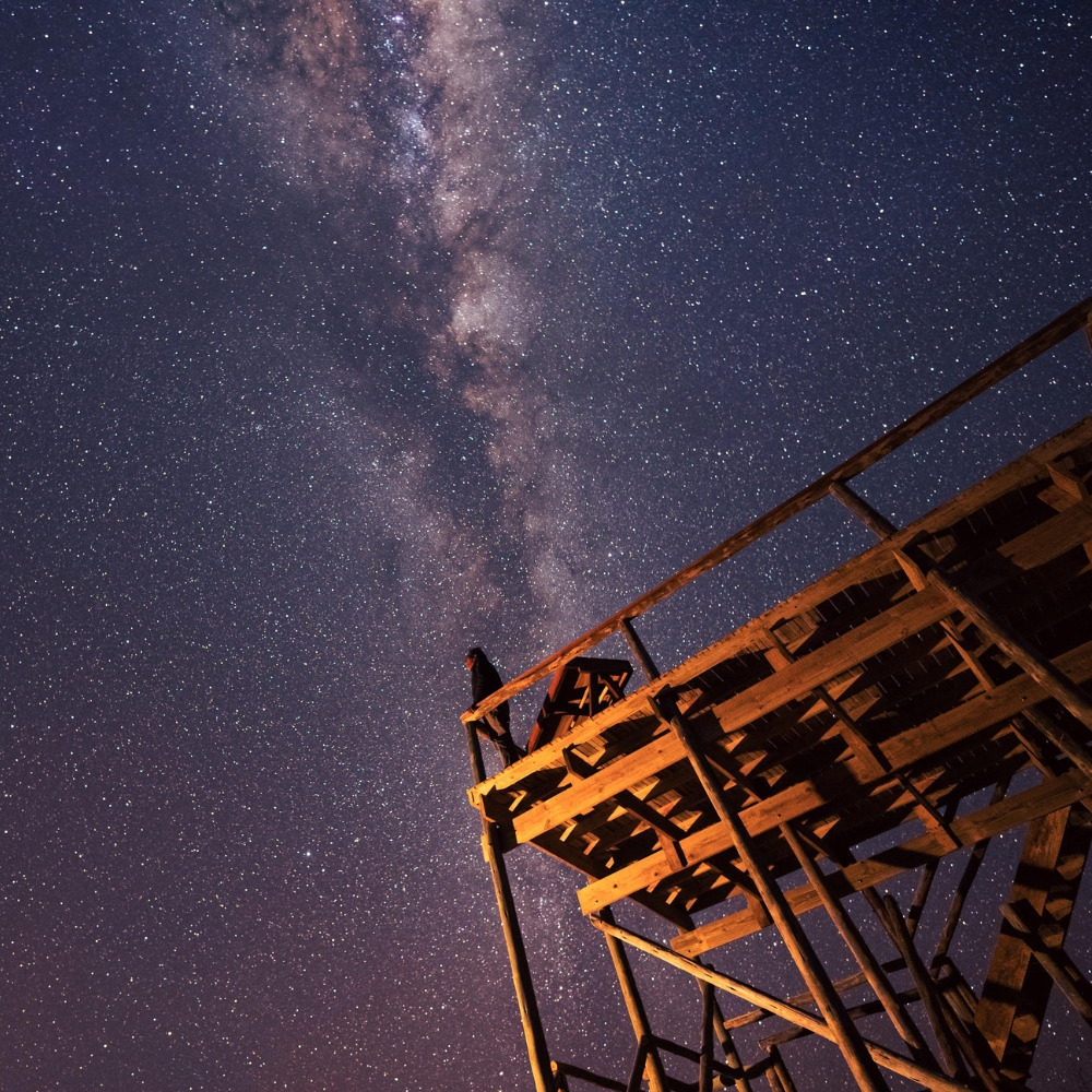 A person on a wooden deck looking up at the starry Milky Way night sky at Dinaka Botswana property.