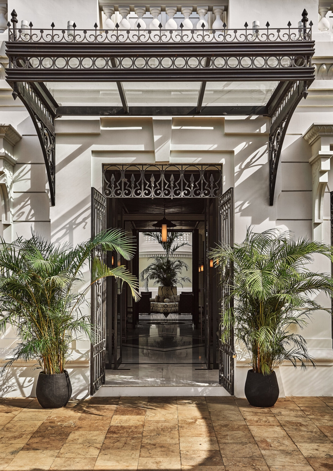 Entranceway with a Beaux Arts doorway and two small palm trees on either side.