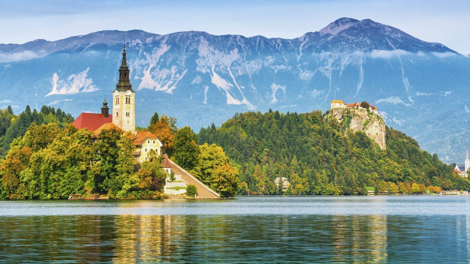 View of church on a small island in the middle of Lake Bled, an alpine lake in Slovenia with snow-capped mountains around it