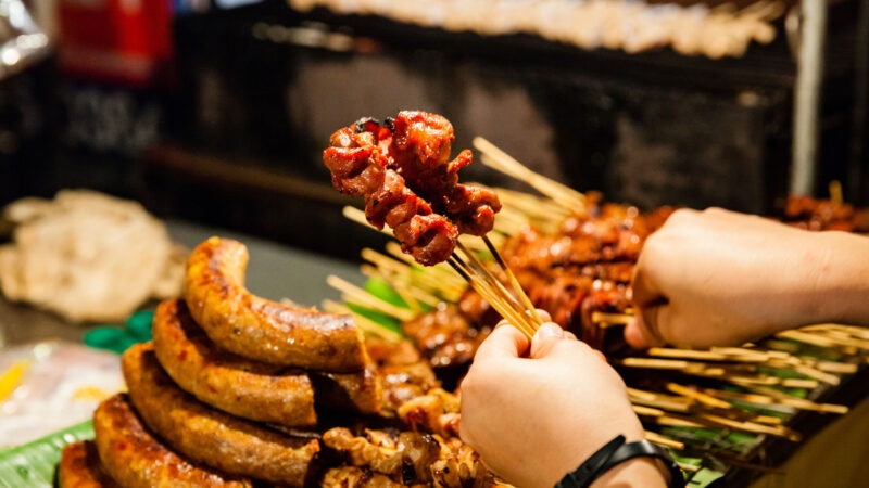 CHIANG MAI, THAILAND: Man buys skewered grilled pork