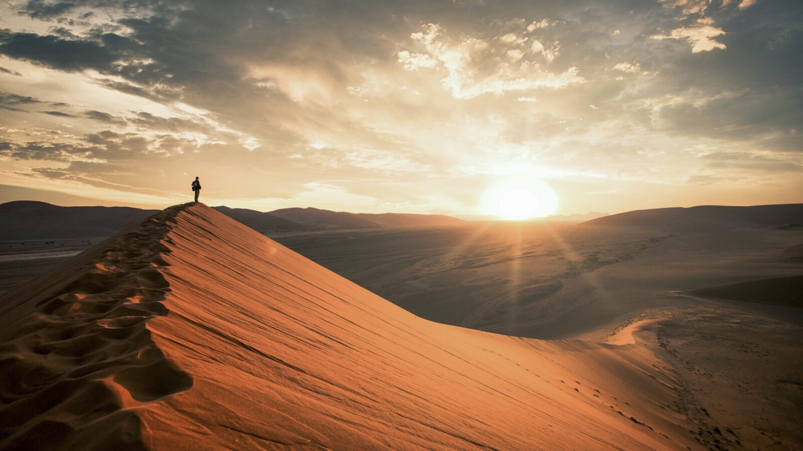 Dramatic sunrise in the Namibian desert with person standing and overlooking the great plains