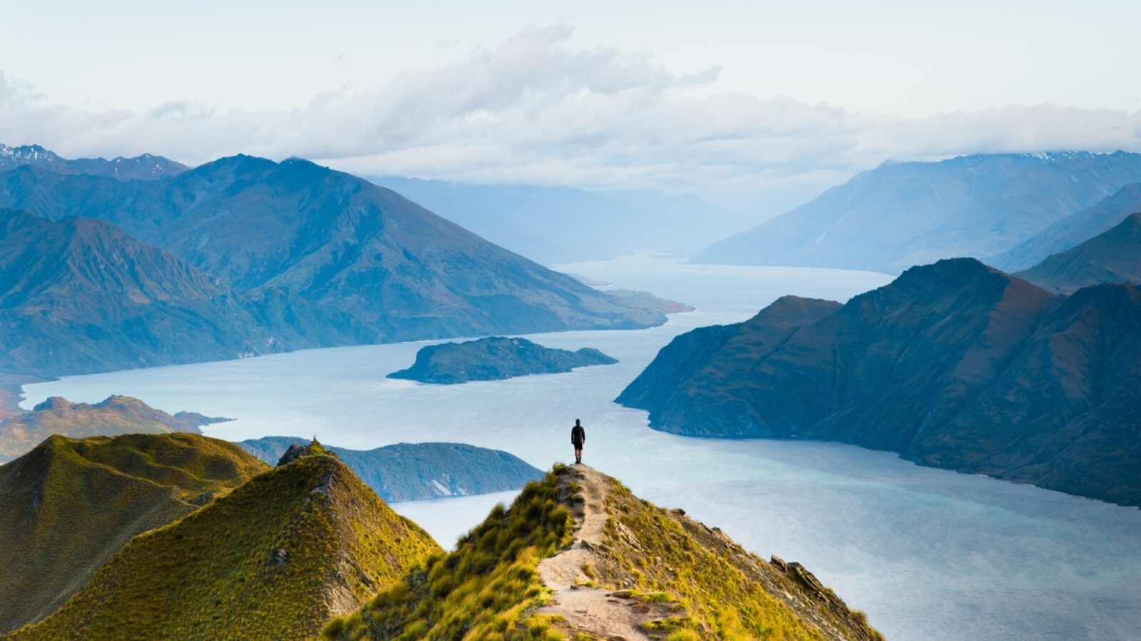 Hiker on Roys Peak overlooking Lake Wanaka and the surrounding mountains