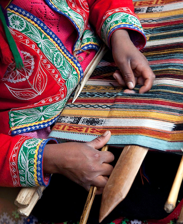 Luxury Peru Tours - A woman's hand weaving traditional, colourful wool fabric in Peru
