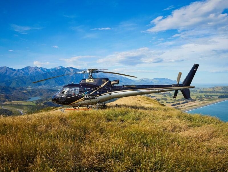 South Pacific Helicopters aircraft parked on a ridge with mountain and ocean views on luxury South Pacific tours.