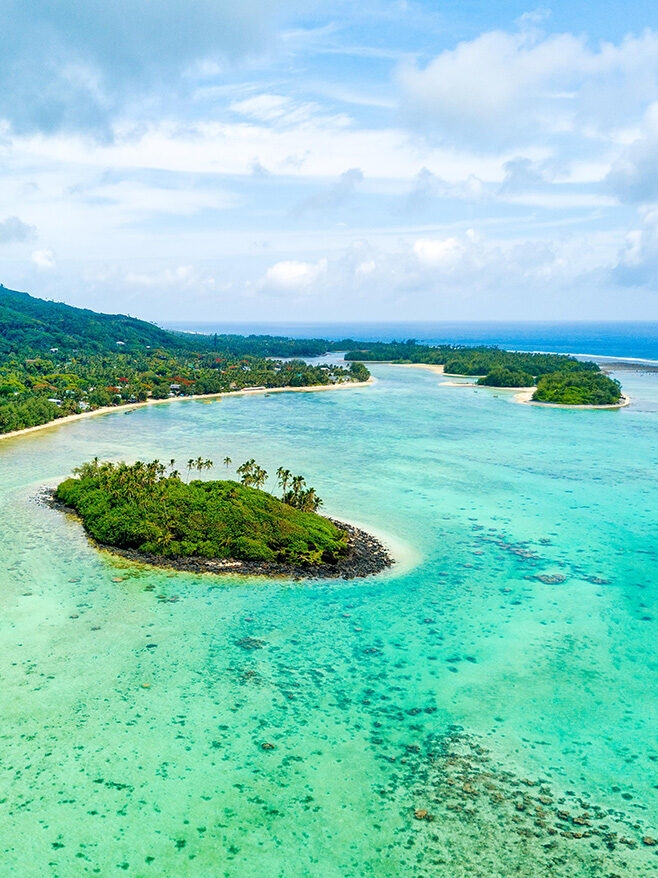 Aerial view of tropical islands and turquoise coral reefs on luxury Australasia holidays.