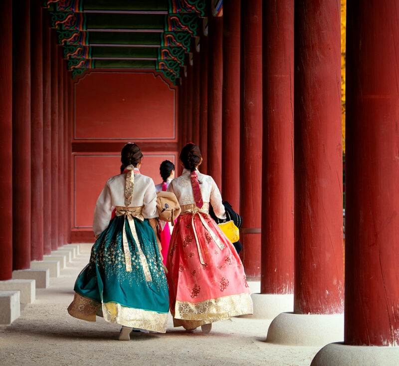 Women in traditional Hanbok walking through a palace during luxury South Korea trips.