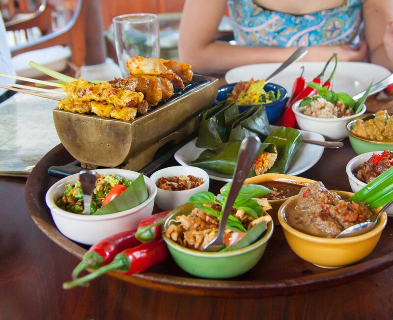 A spread of traditional Indonesian food and satay sticks for luxury Bali holidays.