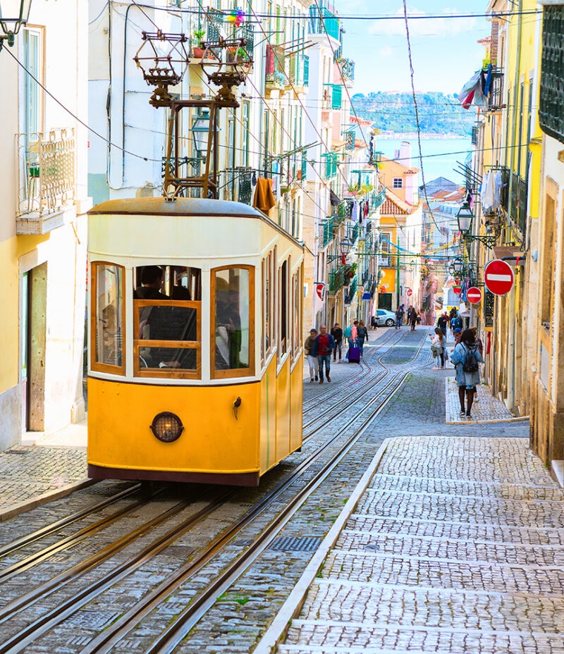 Iconic yellow tram ascending a steep cobblestone street during luxury Portugal tours.