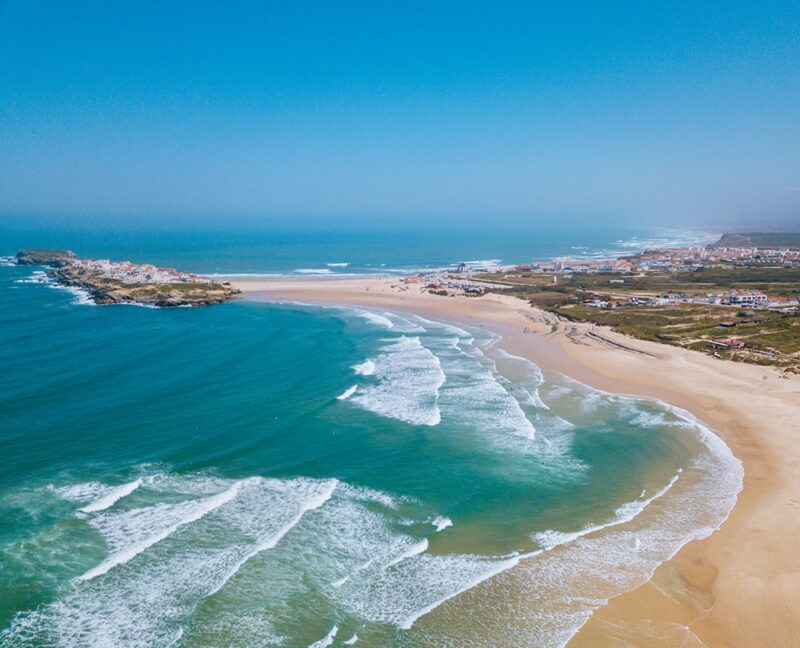 Aerial view of a long sandy beach and breaking waves on luxury Portugal trips.