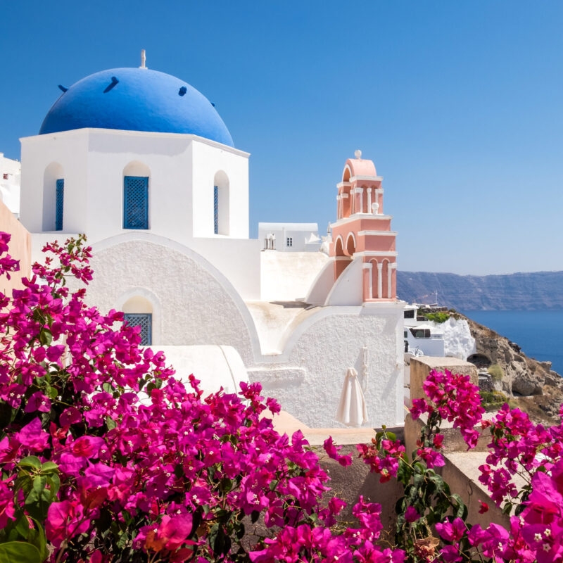 Luxury Grand Tours of Europe - Scenic view of traditional cycladic houses with flowers in foreg