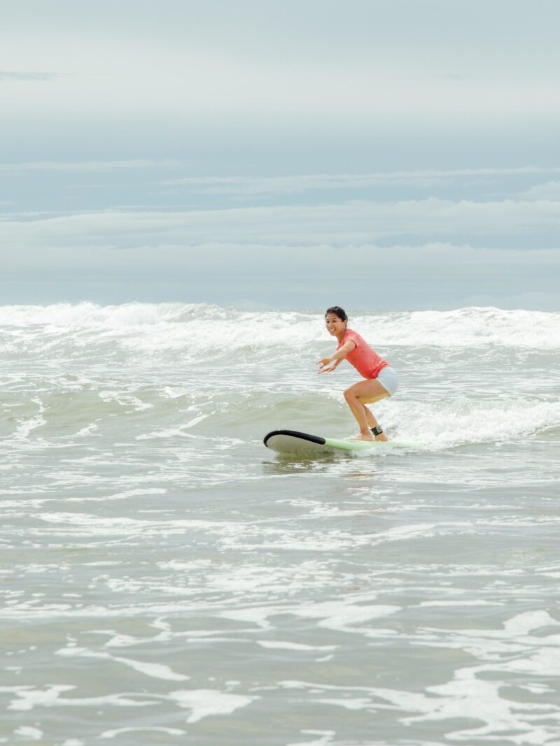 A person in an orange swim suit standing on a surf board on a wave