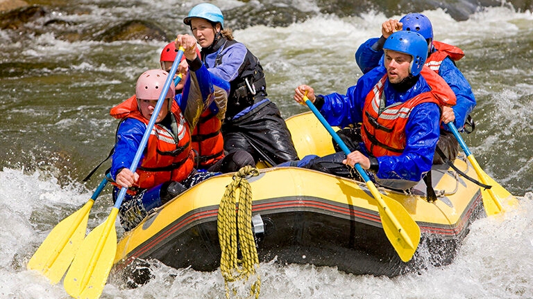A group of people navigate river rapids in a yellow raft during luxury Latin America family holidays.