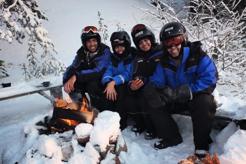 People sitting on a snowy perch in thick winter clothing