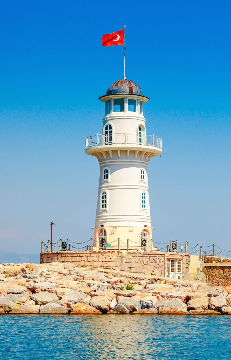 A white lighthouse with a red Turkish flag on top, viewed during luxury Turkey Asia holidays.