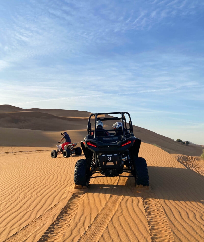 Dune buggy and quad bike driving on orange desert sand dunes for luxury United Arab Emirates trips.