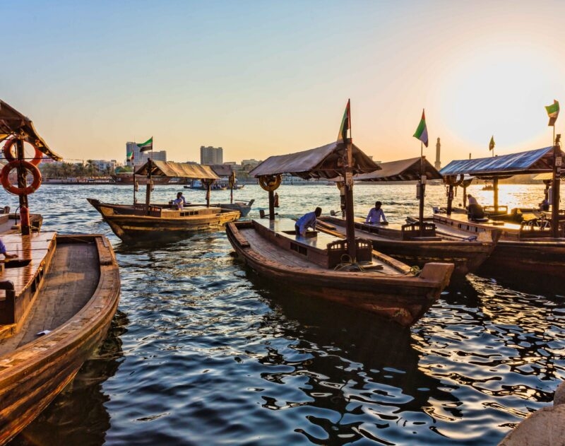 Traditional wooden abra boats on the water at sunset for luxury United Arab Emirates vacations.