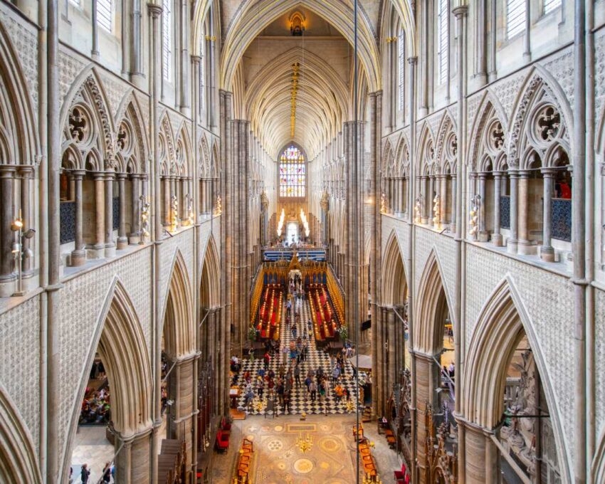 Interior view looking down the long nave of Westminster Abbey featuring high gothic arches and vaulted ceilings.