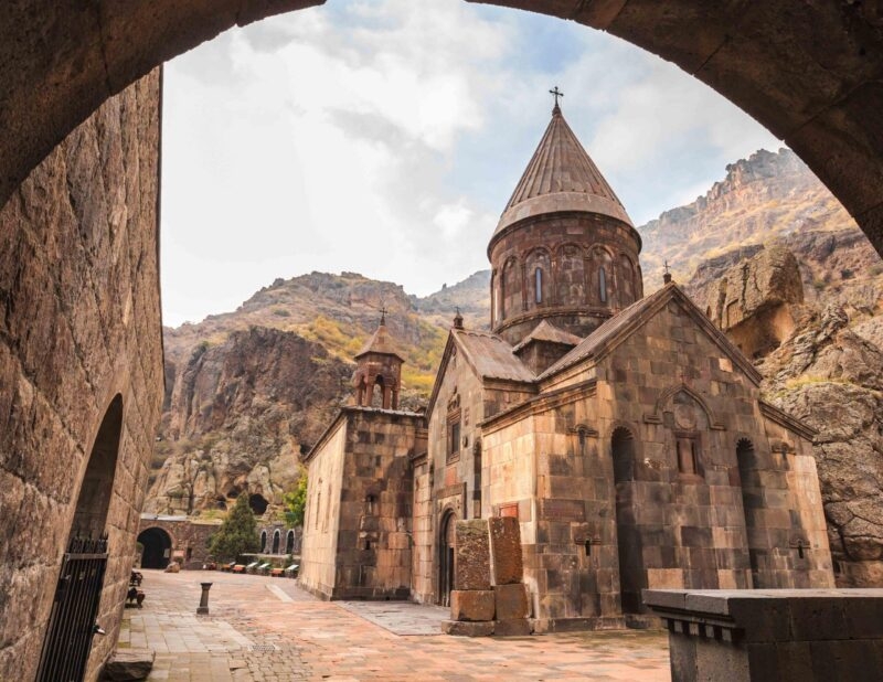 A stone church and courtyard framed by a stone archway on luxury Central Asia trips.