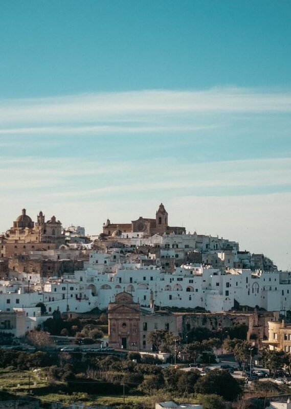 View of a sprawling white hilltop town with historic cathedrals for luxury Puglia holidays.