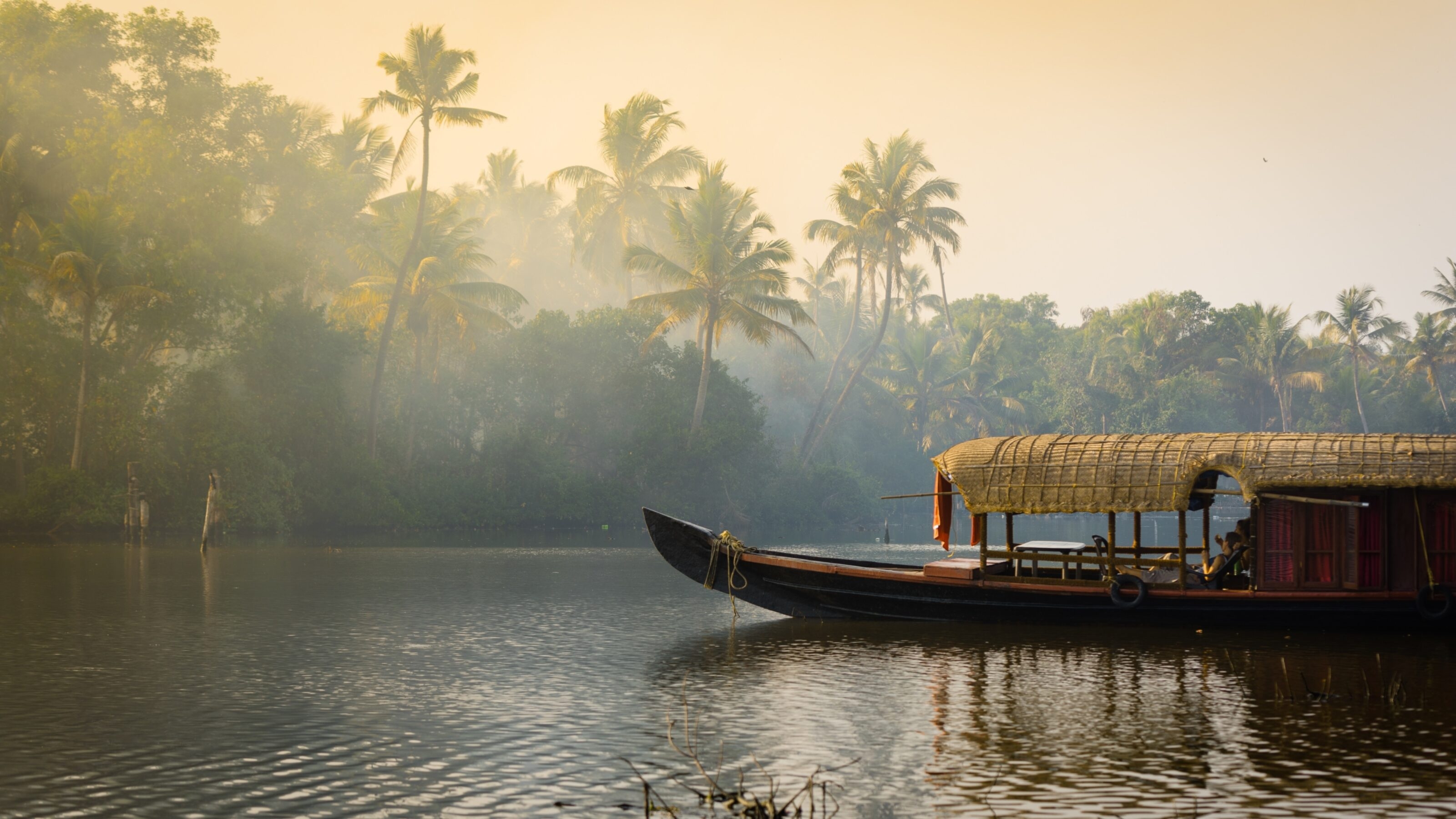 A traditional house boat is anchored on the shores of a fishing lake in Kerala's Backwaters, India.