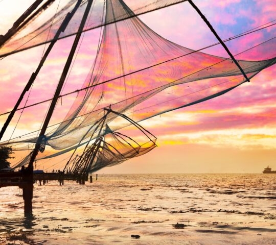 Chinese Fishing nets and small ship at dramatic sunset sky background in Kochi, Kerala, India