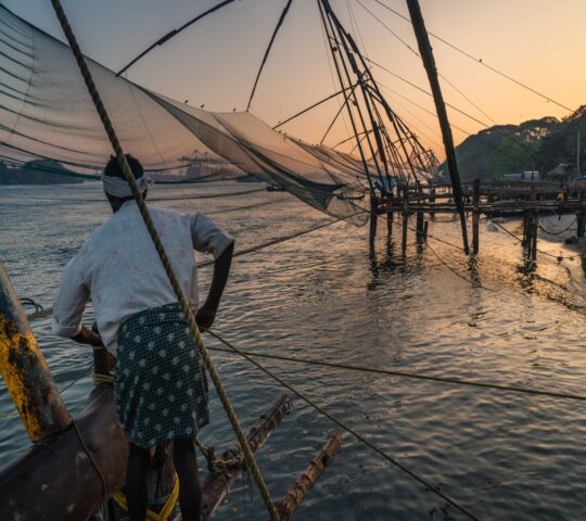 man work at Chinese fishing nets during the Golden Hours at Fort Kochi, Kerala, India