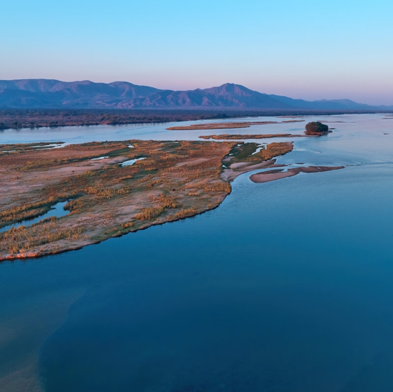 Aerial, east view of Zambezi river during sunset. View on african wilderness, mountains and huge river Zambezi from above. Border river. UNESCO Heritage Site, Mana Pools National Park, Zimbabwe.