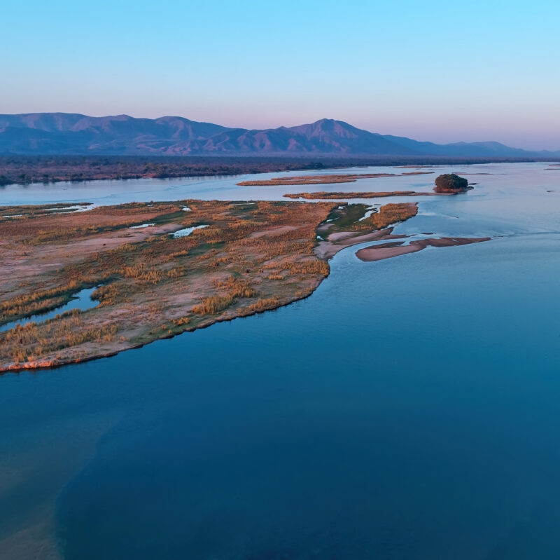 Aerial, east view of Zambezi river during sunset. View on african wilderness, mountains and huge river Zambezi from above. Border river. UNESCO Heritage Site, Mana Pools National Park, Zimbabwe.