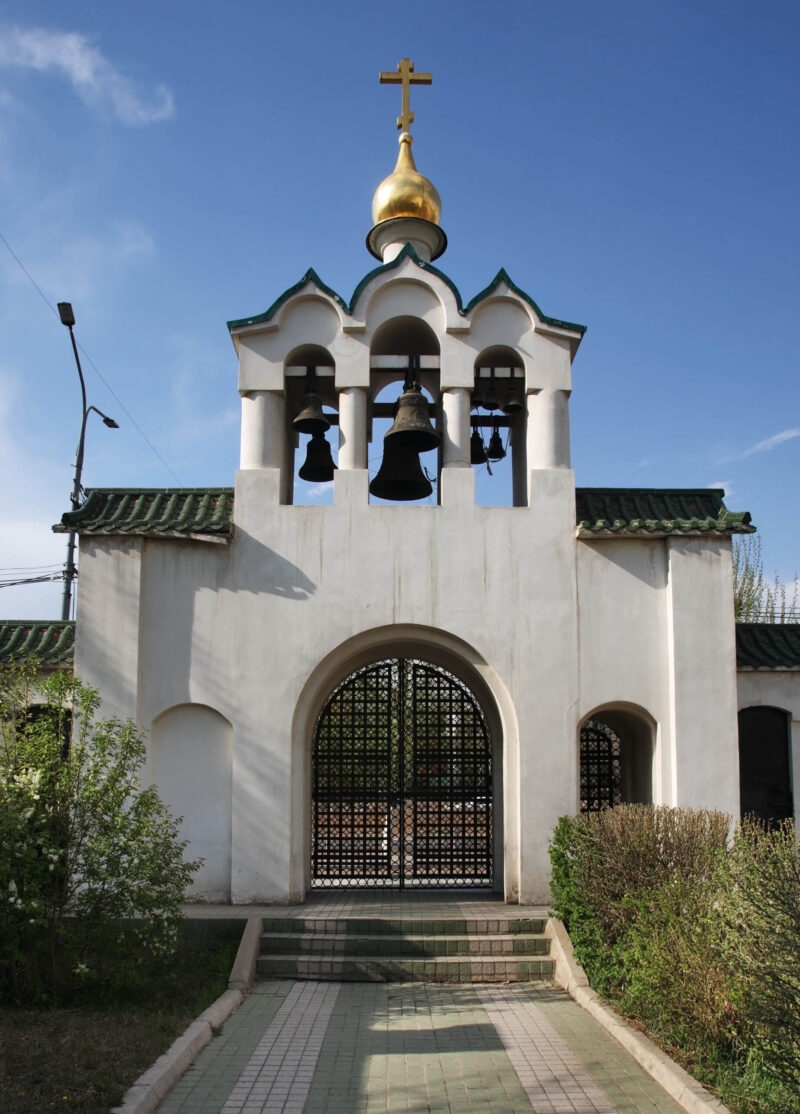 A white arched bell tower with a golden dome, a historical site seen on luxury Mongolia tours.