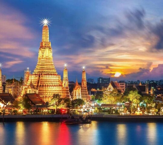A view of Wat Arun temple along the Chao Phraya river at night in Bangkok