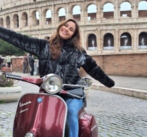 Person on a red Vespa scooter in front of the Colosseum.