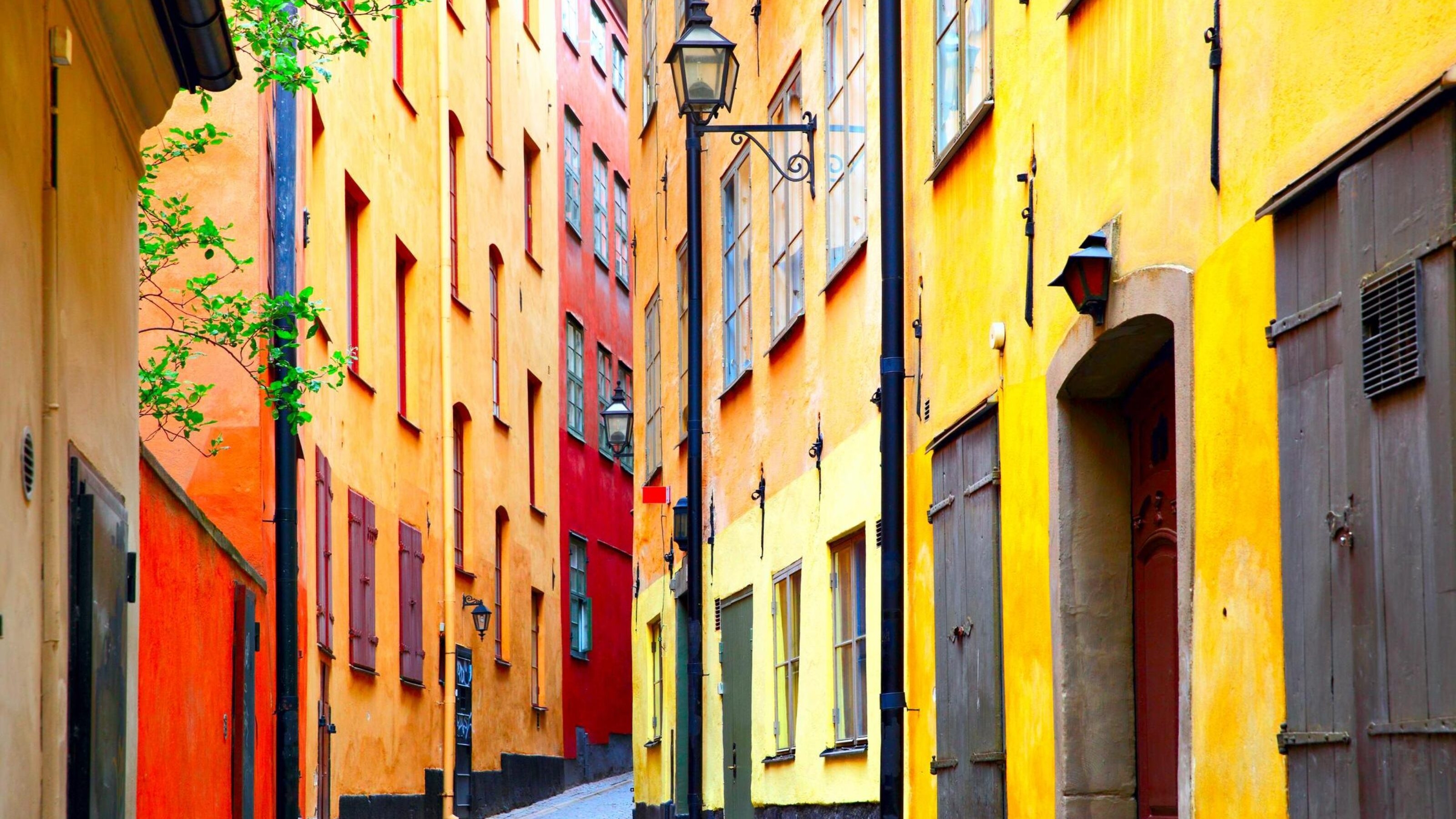 Colorful narrow European street with bright yellow and red buildings and a street lamp.