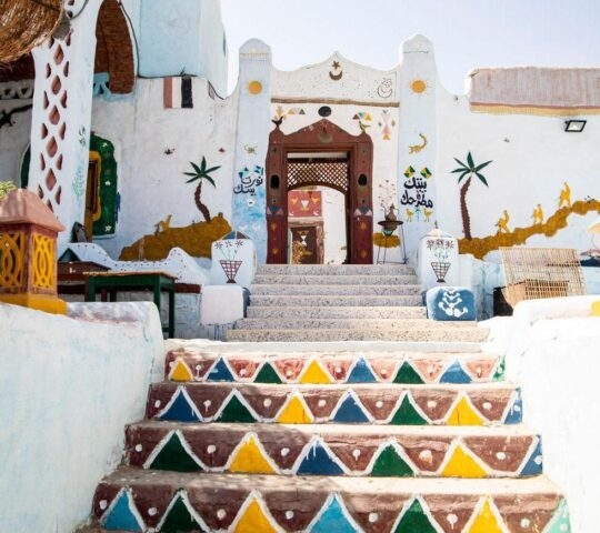 Colorfully painted staircase leading to a traditional building with ornate door and wall decorations.