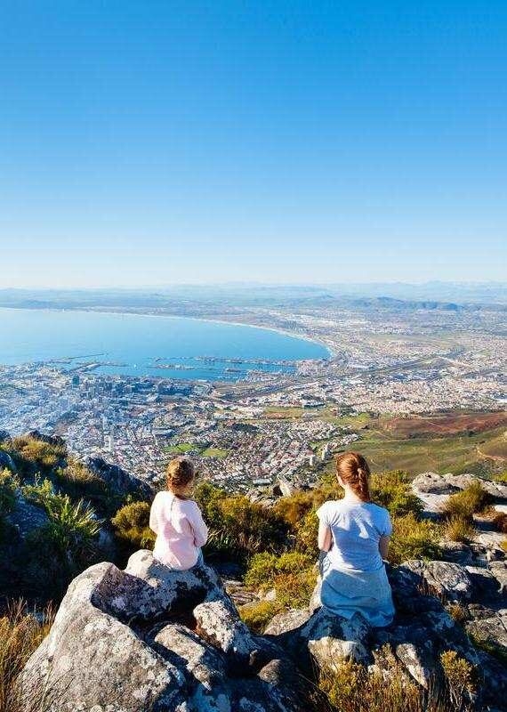A person hiking through a rocky landscape at sunset during luxury Cape Town holidays.