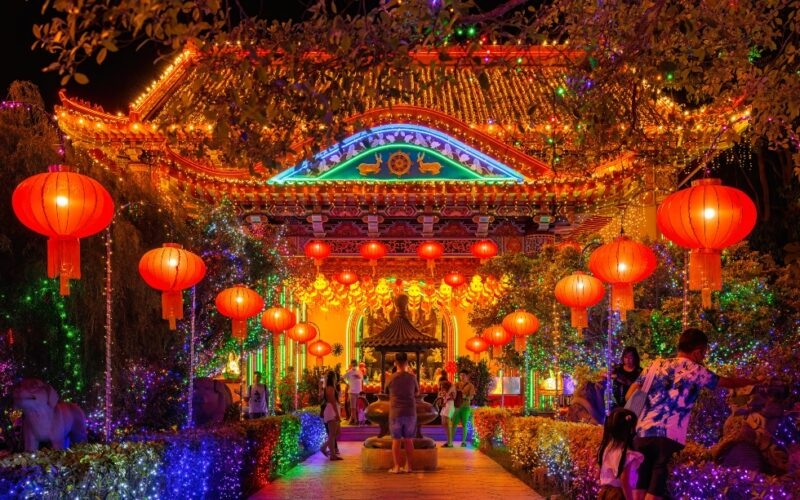 Traditional Chinese architecture adorned with bright lights and red lanterns at nighttime, with visitors strolling.