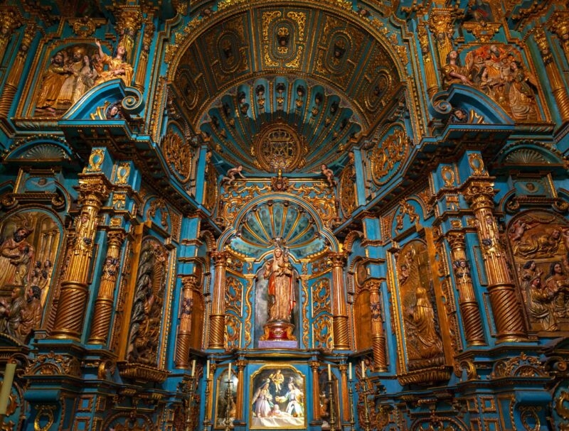 Ornate blue and gold baroque church altar with sculptures and religious art.