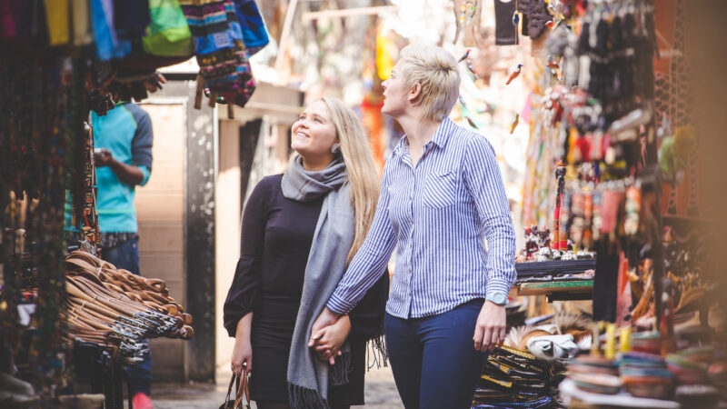 A couple walking hand-in-hand through a colorful traditional market on luxury Africa honeymoon tours.