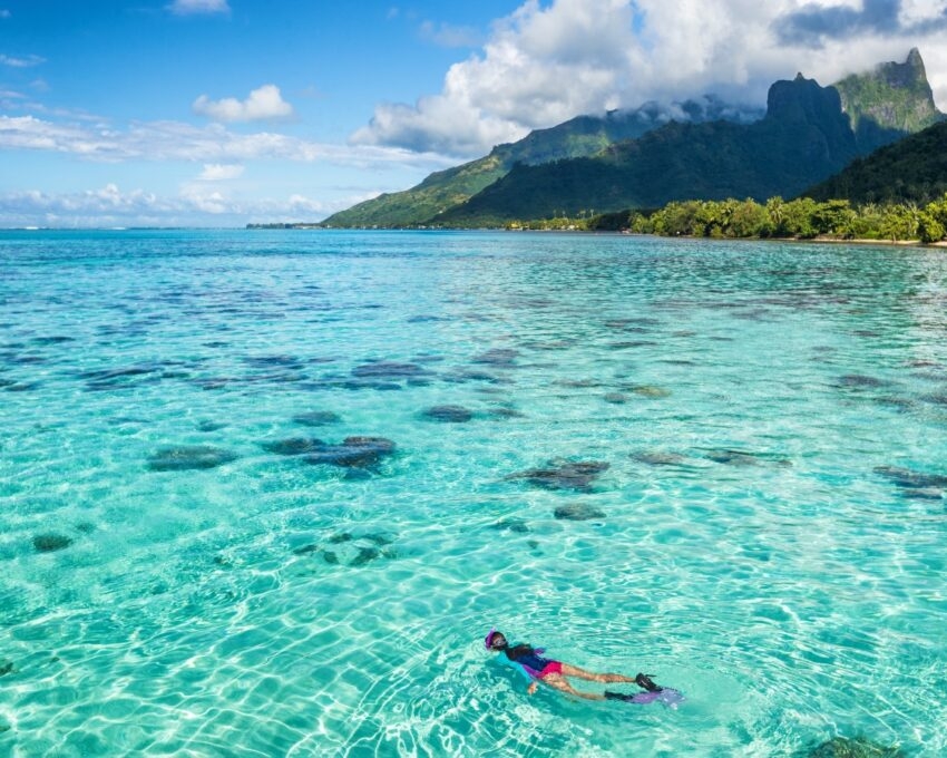 Luxury travel vacation tourist woman snorkeling in Tahiti ocean, Moorea island, French Polynesia.