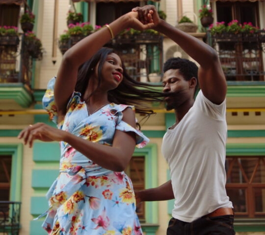 Happy afro dancers curling in latino dance in city. Couple dancing on street