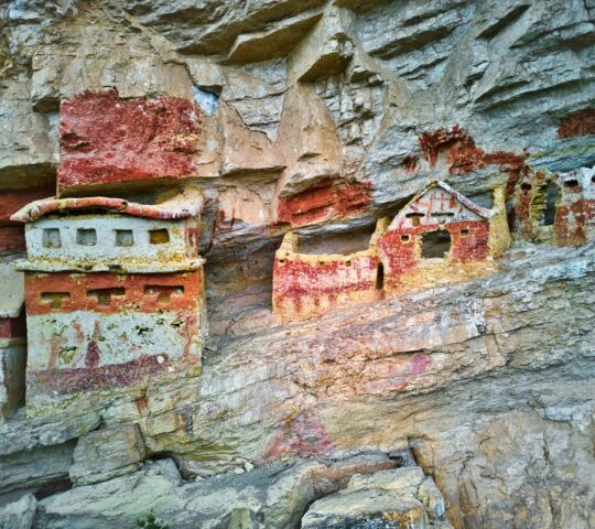 Colorful ancient cliffside tombs embedded in a rocky surface.